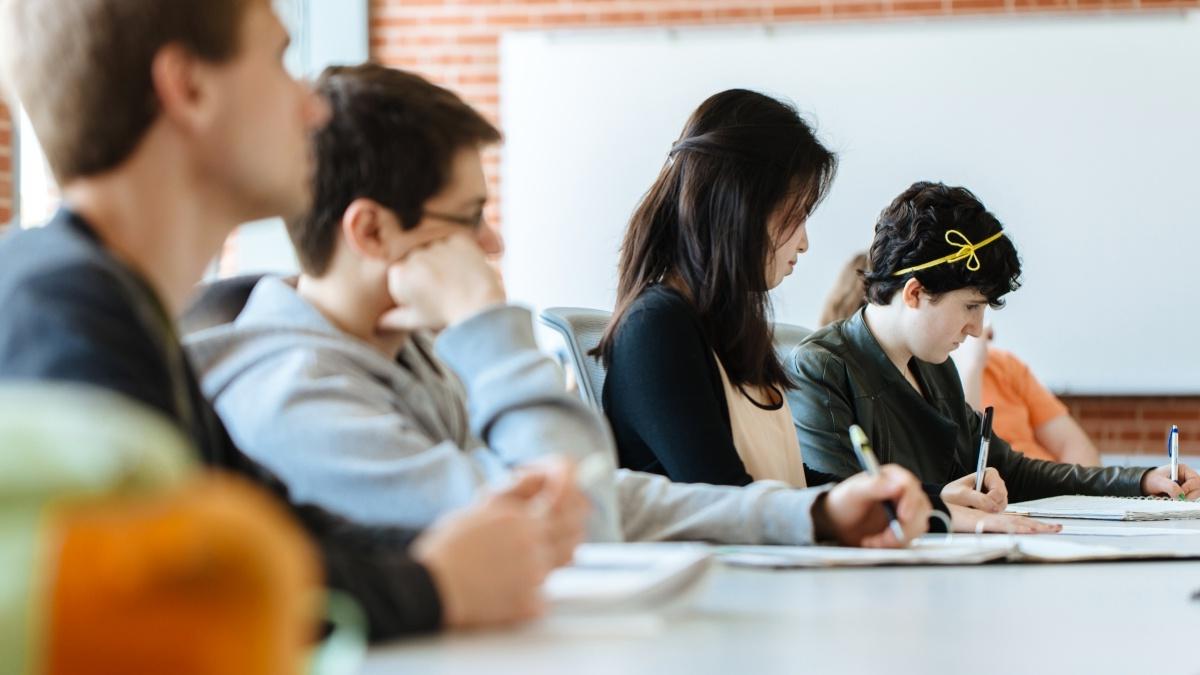 Students sitting at long table listening to lecture